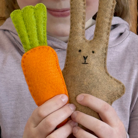 Child holding a felt carrot and rabbit toy