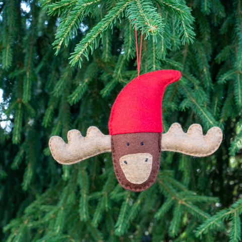 Moose ornament with a red hat hanging on a Christmas tree.