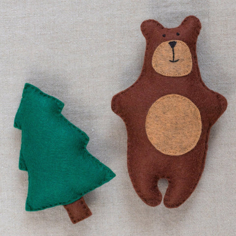 Felt bear and tree toy on a linen fabric background