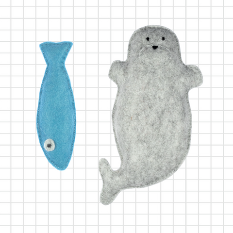 Plush toy seal and blue fish on a grid background