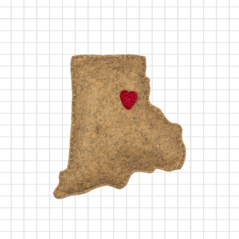 Felted brown animal-shaped mat with a red heart on a grid background