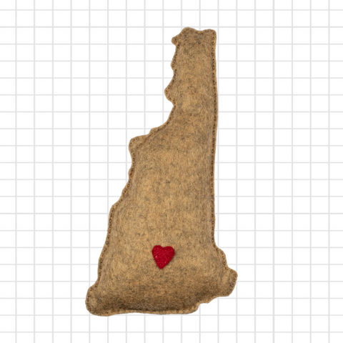 Brown felt shape of a state of new hampshire with a red heart on a grid background