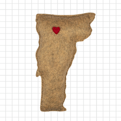Felted animal-shaped object with a red heart on a grid background
