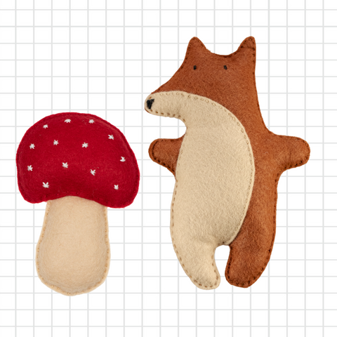 Felt fox and mushroom toy on a grid background
