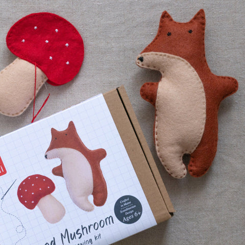 Felt fox and mushroom toys with packaging on a gray surface