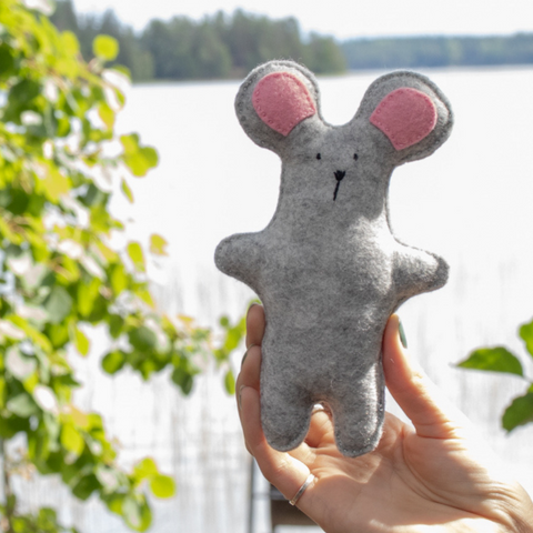Gray mouse plush toy held by a Finnish lake