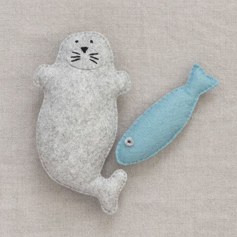Felt seal and fish toy on a neutral fabric background
