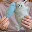 Child holding a felt fish and seal toy against a pink hoodie background