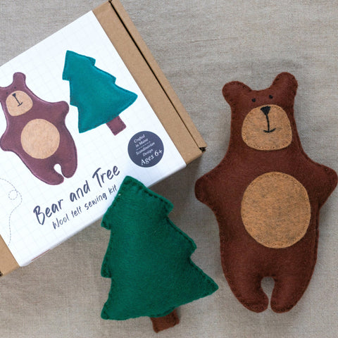 Felt bear and tree toys with a sewing kit on a neutral background