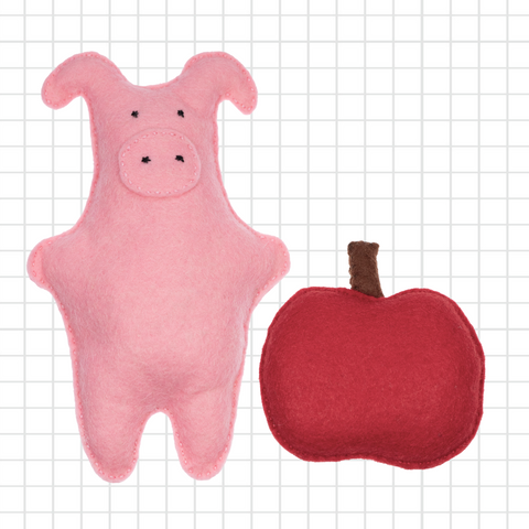 Pink pig-shaped toy and red apple-shaped toy on a grid background