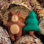 Felt brown bear and green tree toy on a wooden log