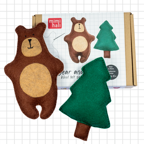 Felt bear and tree toys with packaging on a grid background