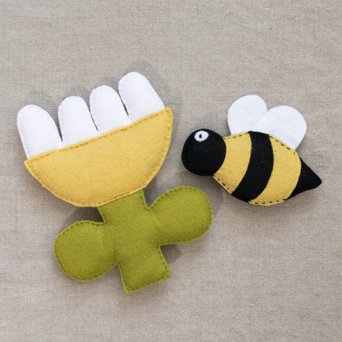 Felt bee and flower toy on a textured neutral background