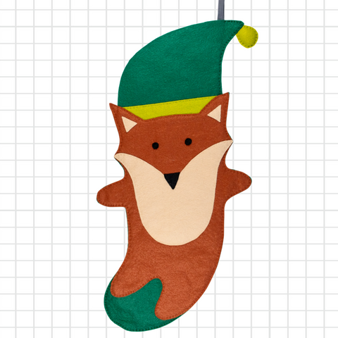 Felt craft of a fox wearing an elf hat on a grid background
