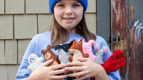 Child holding plush toys in front of a wooden door