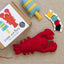 Red lobster and buoy felt toys with sewing kit packaging and threads on a neutral background