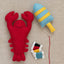 Red lobster plush toy and blue and yellow striped buoy and threads on a neutral fabric background