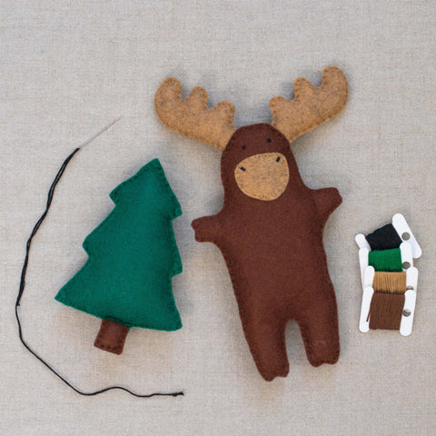 Felt moose and tree toy with threads on a neutral background
