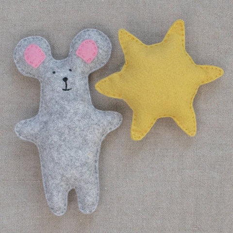 Felt mouse toy and yellow sun on a neutral fabric background
