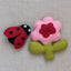 Felt ladybug and flower on a textured neutral background