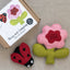 Felt flower and ladybug with packaging on a neutral surface