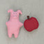 Pink felt pig and red apple on a neutral fabric background