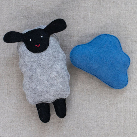 Felt sheep toy and blue cloud on a neutral background